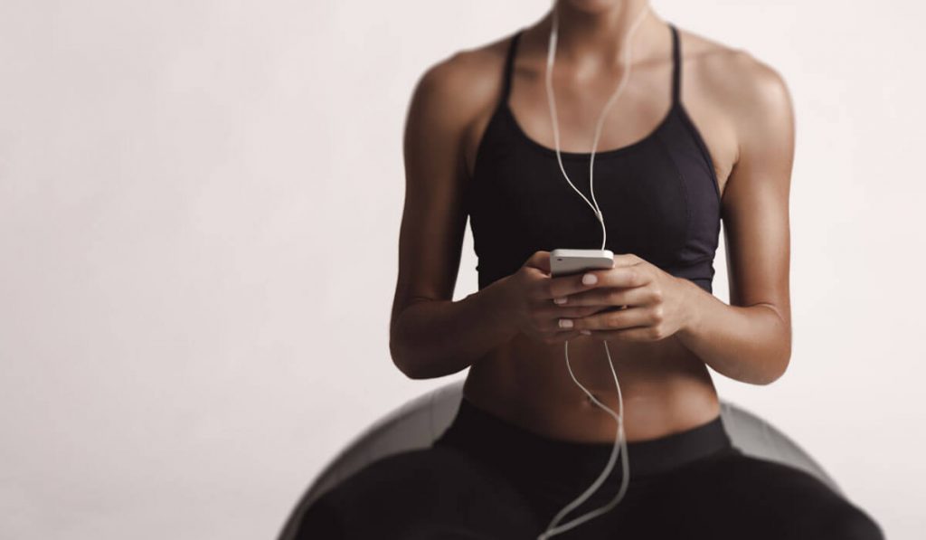 gym girl on her phone while sitting on yoga ball