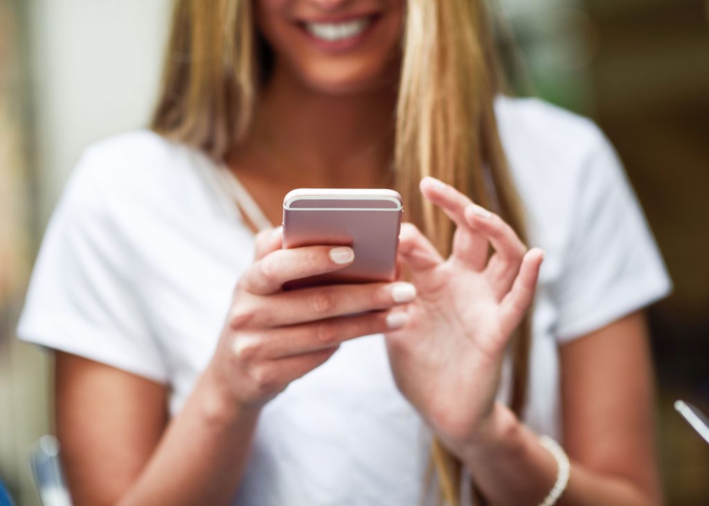 girl in white shirt on her phone sending direct messages